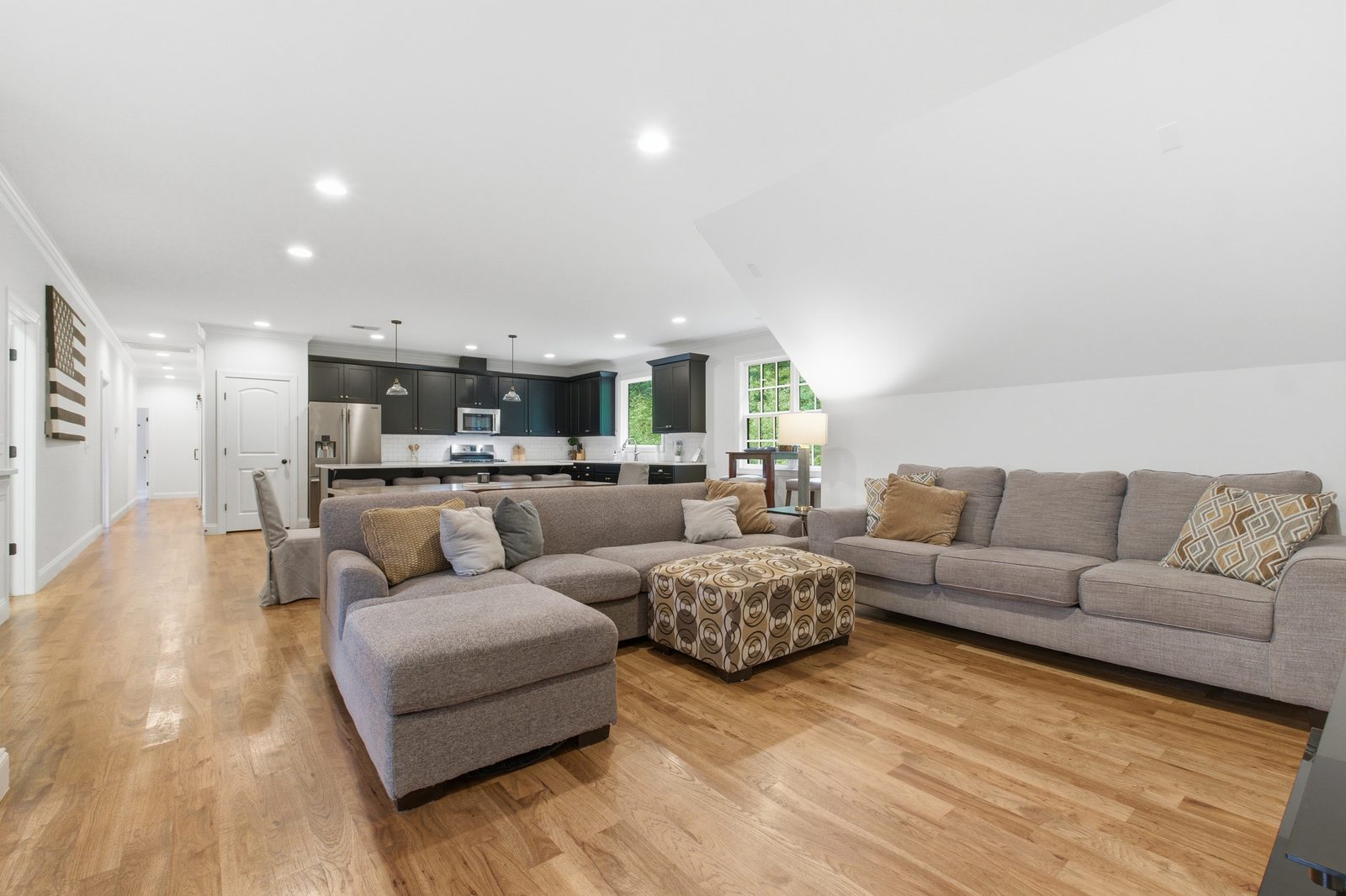 Open upper level living and dining area with wood floors and a vaulted ceiling
