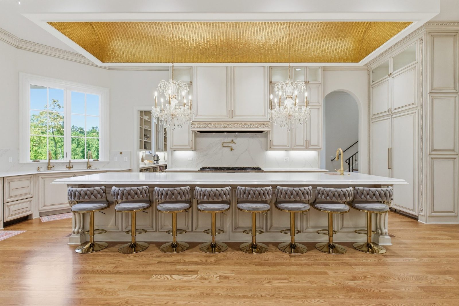 The chef's kitchen — gold mosaic barrel vault ceiling, twin crystal chandeliers, and marble island